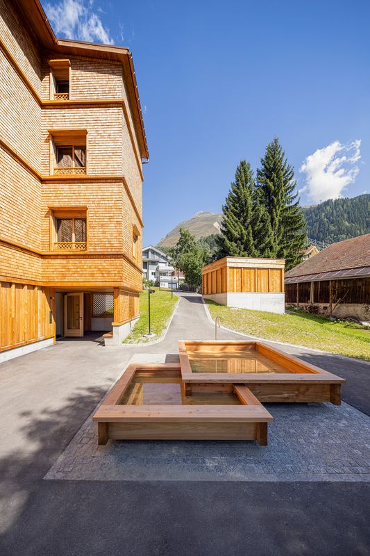 Neubau Casa Depuoz, Sedrun – Holzbrunnen als zentrales Gemeinschaftselement – Foto: Ingo Rasp