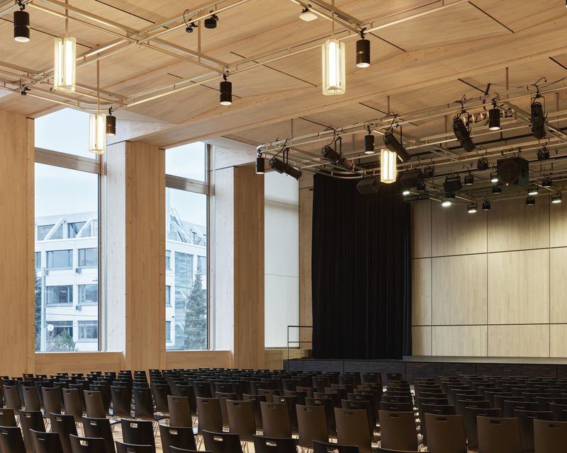 Erweiterungsneubauten Kantonsschule Limmattal, Urdorf – Hallentrakt: Aula als eingestellter, hölzerner Raum als Abbild der dahinterliegenden Tragstruktur – Igor Ponti