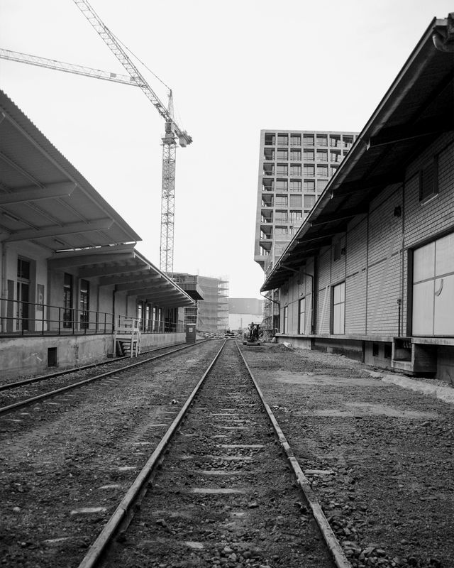 Kunsthaus Baselland – Ausgangslage Bestand Dreispitzhalle: Das Gelände ist geprägt von seiner typischen Bandstruktur. Lange Gebäude zur Lagerung von Gütern stehen zwischen Zufahrtsstraßen und Eisenbahnschienen. – Buchner Bründler Architekten 