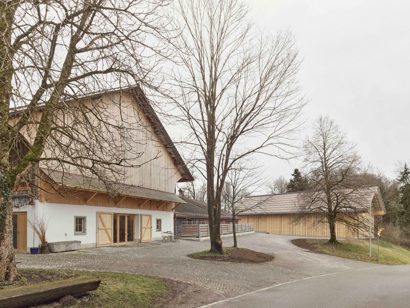 Ökonomiegebäude Lützelsee – Die neue Remise fasst den Hofplatz vor dem alten Stall mit integriertem Hofkiosk – Foto: Andreas Graber