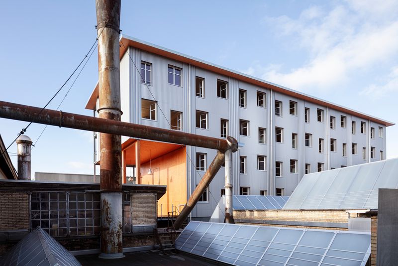 Gebäude 181 Lagerplatz – Fassade mit springenden Wohnatelierfenstern, saniertem Hallendach und Blick zur Terrasse für Alle – Lucas Peters