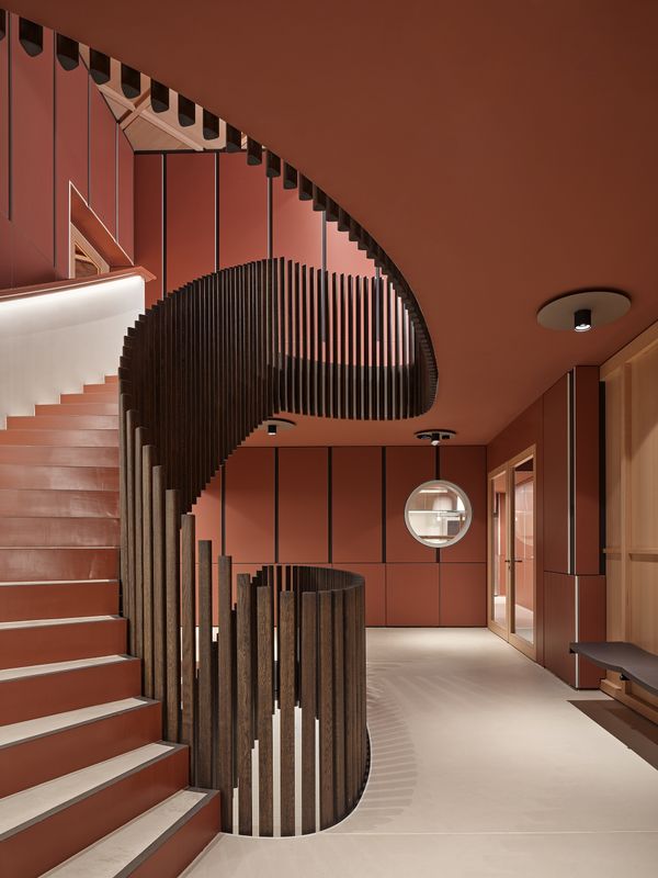 Klanghaus Toggenburg am Schwendisee – Die rhythmisch hinaufschwingenden und gebeizten Eichenstäbe vertonen die Trittverhältnisse in Ober- und Untergeschoss. Umgeben sind sie von einem Negativtäfer aus Gipsfaserplatten – rote Flächen, weisse Kanten und dunkle, zurückliegende Schatten mit Drehsinn. – Roland Bernath