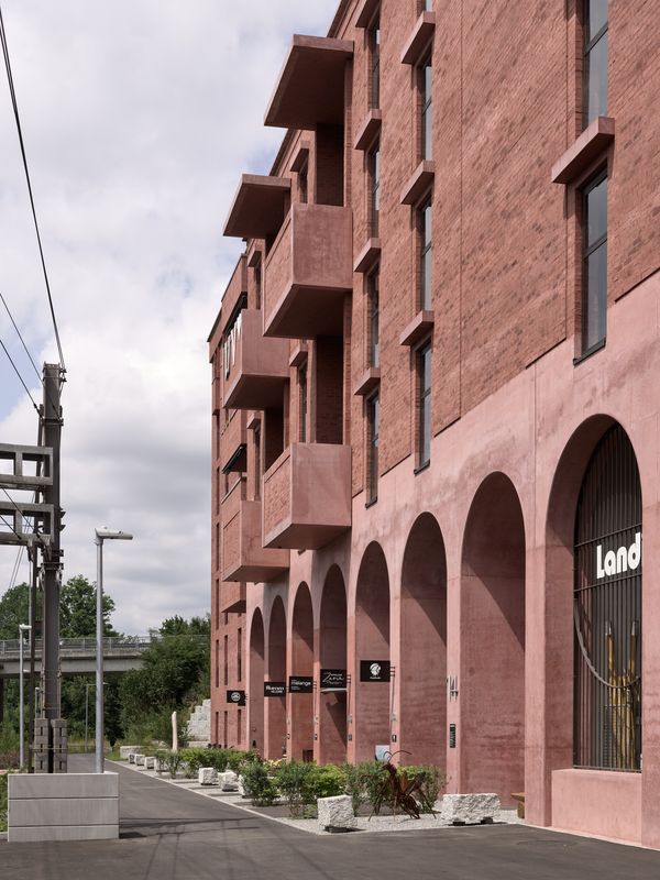 Chäsimatt – Bahnseitig gelegene Ateliers und der Landi Aussenverkauf adressieren den Wanderweg zum Naturschutzgebiet hin. Die Lärmschutzfassade mit den doppelhohen Aussenräumen ermöglichen ein lärmberuhigtes aufhalten zur südlich gelegenen Bahn. – © 2018 by Ariel Huber / EDIT images